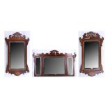 A pair of Georgian style mahogany bevelled mirrors with pierced pediments and carved and gilded