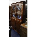 A very late Victorian mahogany inlaid bookcase cabinet, enclosing adjustable shelves with a pair