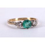 An 18 carat yellow gold, emerald, and diamond ring, set round cut emerald flanked by two round cut