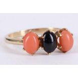 A 14 carat yellow gold, onyx, and coral three stone ring. Size: R Weight, 3.3g