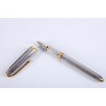 Cartier, Paris. A stainless steel and yellow metal fountain pen, having vertically ribbed body and