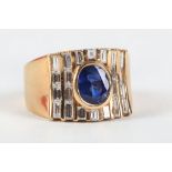 A yellow metal, diamond, and sapphire ring, set oval cut sapphire, flanked by baguette cut diamonds.