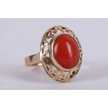 A Continental 18 carat yellow gold and coral ring, having oval cabouchon stone within openwork