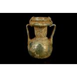 A ROMAN GREEN GLASS TWO HANDLED JAR Circa 3rd-4th Century A.D. With a long neck, wide spout and