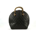 RARE CHANEL VINTAGE ROUND TOTE, c.1992, black quilted leather with two short stiff gilt metal and