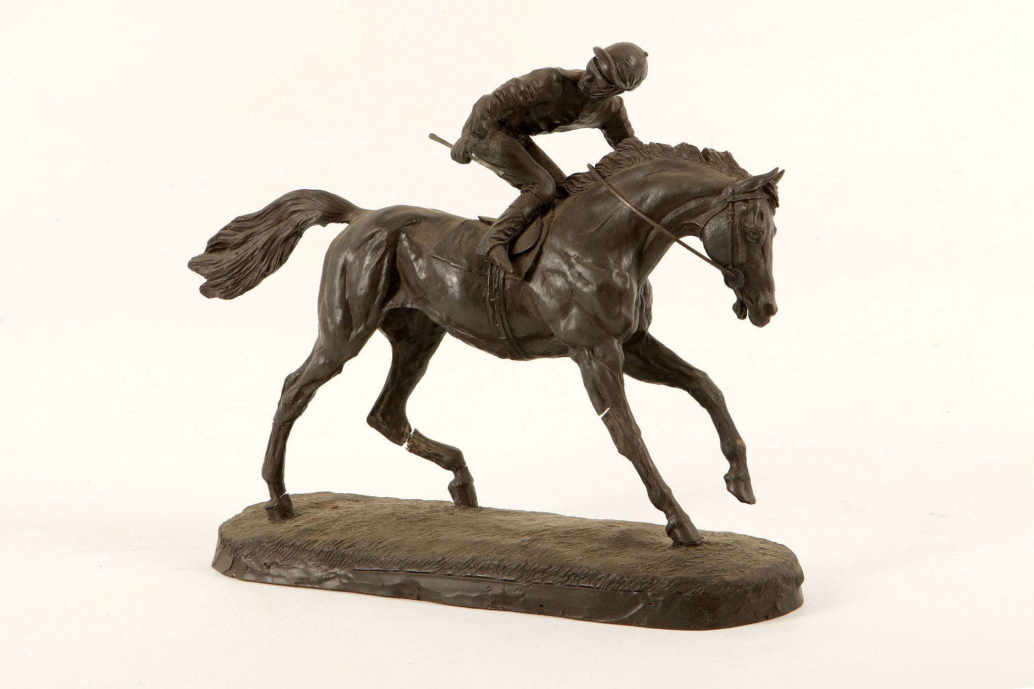 A Spelter figure of a jockey on horseback.