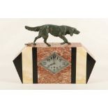 AN ART DECO VARIEGATED MARBLE CLOCK, with bronzed spelter figure of a dog above (43cm wide).