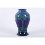 A WILLIAM MOORCROFT POTTERY BALUSTER SHAPED VASE, in 'Moonlit Blue', c.1925, green painted