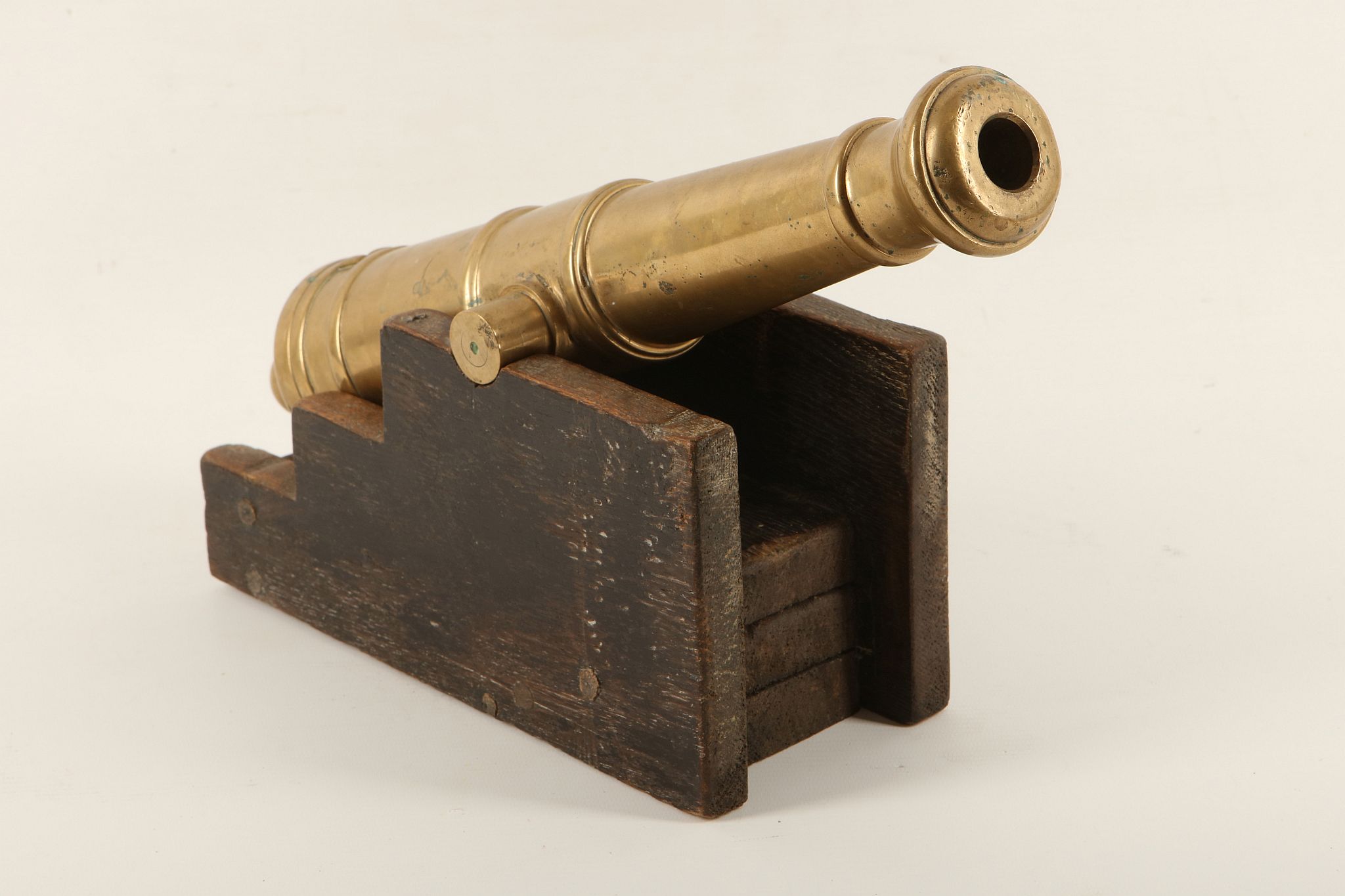 A bronze desk top cannon on wooden base.