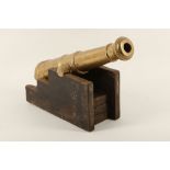A bronze desk top cannon on wooden base.