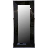 A LARGE MODERN CONTEMPORARY MIRROR, with black glass surround with floor standing feet (205cm x