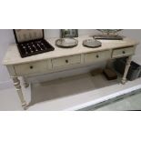 A cream painted side table with four drawers raised on turned legs.