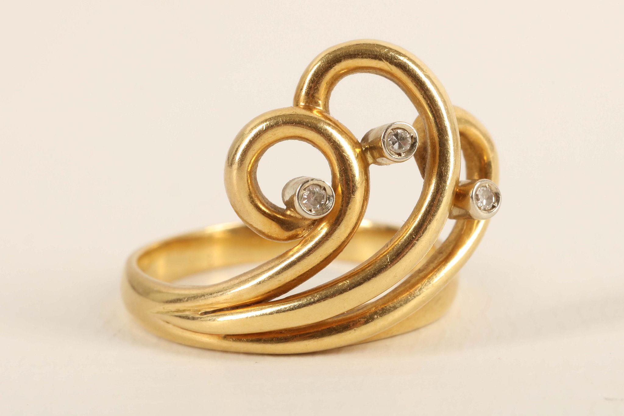 An 18ct gold and diamond set wave scoll dress ring. Size: N. 6.36g,