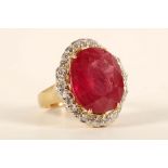 An 18ct gold, ruby and diamond cluster ring, the oval faceted ruby framed by round cut diamonds.