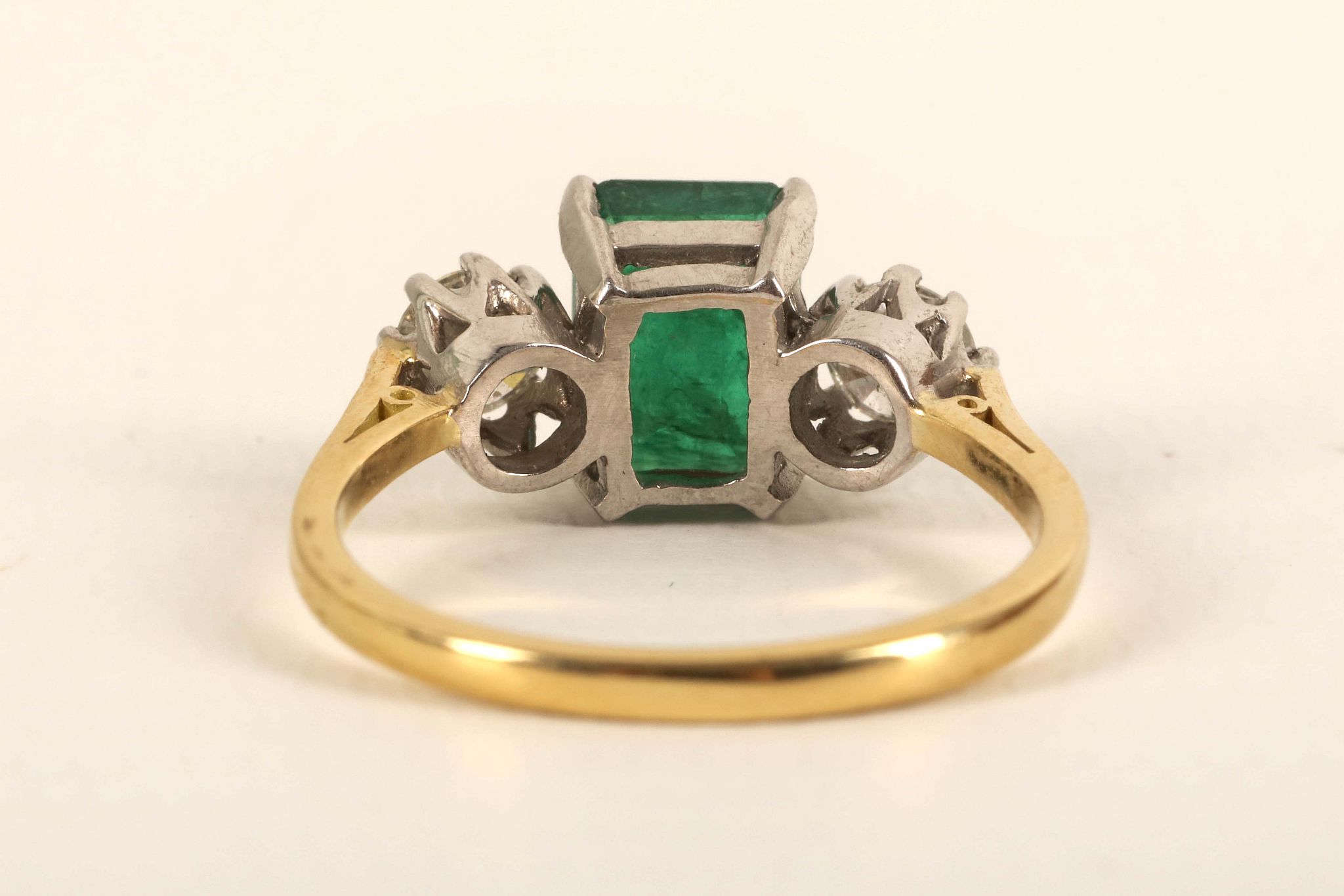 An 18ct gold, emerald and diamond three stone ring, the emerald cut main stone flanked by - Image 2 of 2