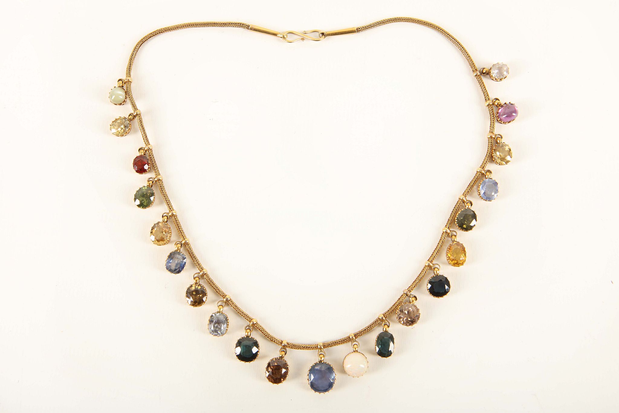 A c.1900 gold and multi gem necklace, the fox tail chain loop mounted with twenty one claw set gem