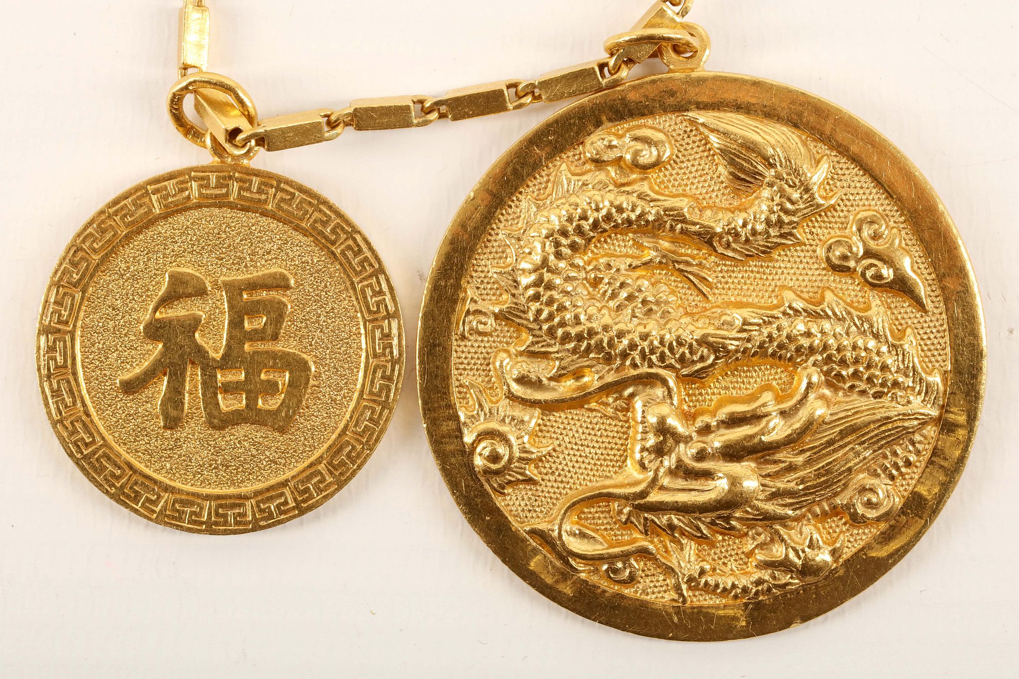A Chinese high carat gold pendant (marked 9999), with scaled coiled dragon decoration, on a flexible