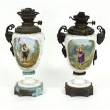 A pair of French porcelain oil lamps with gilt figures in landscape,