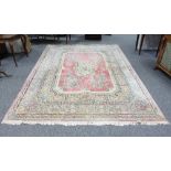 A Persian wool carpet, the central pink field within a scroll and floral border,