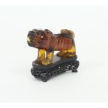 A Chinese amber coloured carved lion on a wooden stand, 11cm high Condition Report: There are cracks