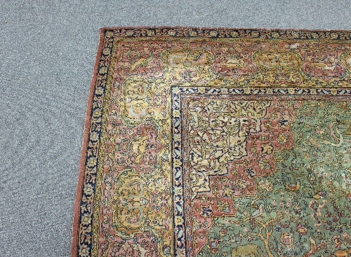 A large Persian rug worked with forest scenes on a green border with central red medallion within - Image 3 of 3