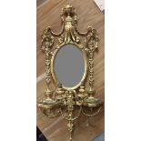 A Victorian plaster gilt girandole with two lights and two shelves above an oval mirror,
