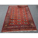 An Eastern rug of Bokhara design, the red ground field of 27 elephant foot medallions,