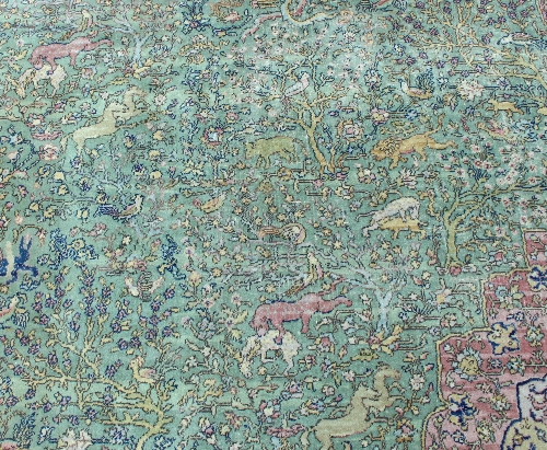 A large Persian rug worked with forest scenes on a green border with central red medallion within - Image 2 of 3