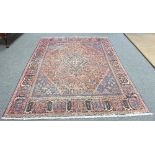 An Afghan carpet with central indigo lozenge medallion and spandrels on a madder ground,