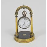 A silver cased pocket watch mounted on a brass desk top stand with circular base and arched top