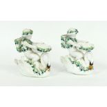 A pair of Continental porcelain figural vases modelled as putti riding swans,