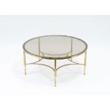 A circular brass low table with glazed top, on five reeded legs and shaped stretcher,