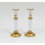 A pair of gilt metal mounted candlesticks, each with white opaque glass stems, the mounts cast