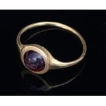 An intaglio carved ring, the circular cabochon depicting a standing figure,