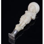A carved ivory desk seal modelled as a boy in Victorian dress, the matrix with monogram,