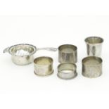 A silver tea strainer and stand, Birmingham 1939, four napkin rings and a small beaker,