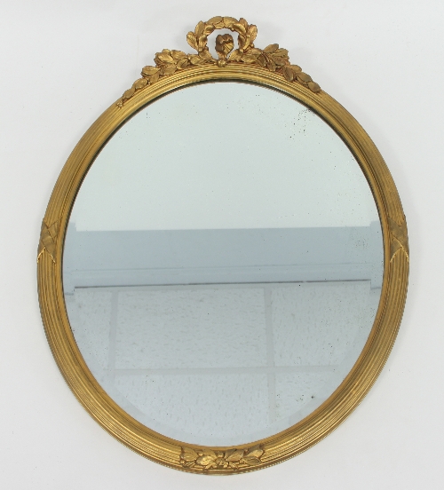 An Edwardian giltwood wall mirror, of oval form, with floral carved frieze and ribbon detailing,