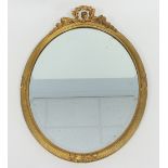 An Edwardian giltwood wall mirror, of oval form, with floral carved frieze and ribbon detailing,