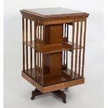 An Edwardian oak two-tier revolving bookcase with tooled leather inset top, raised on brass castors,
