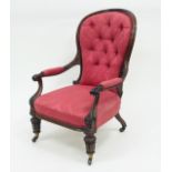 A Victorian walnut armchair with deep button back upholstered seat and padded arms on carved and