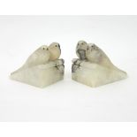 A pair of Art Deco alabaster book ends, each carved with a pair of budgerigars on a sloping ledge,