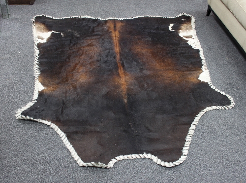 A cowhide rug with wide stitch border,