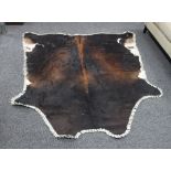 A cowhide rug with wide stitch border,