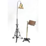 A Victorian reading stand with adjustable brass column on a wrought iron quadruple support and a