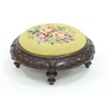 An oak circular foot stool with carved surround on four turned legs, gros point needlework,