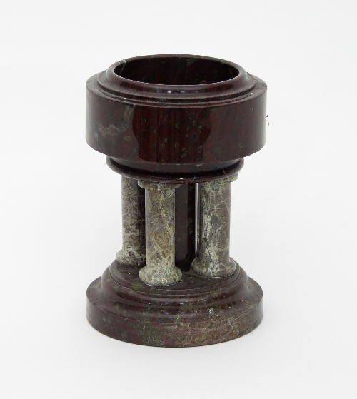 A variegated marble model of a font, with four pillar supports on a circular base,