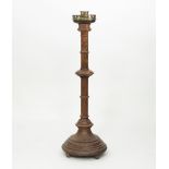 A Victorian gothic oak standard candlestick with turned collars and brass crowned sconce,