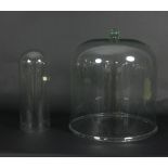 A large glass bell-shaped cover, 42cm high x 39cm diameter and a smaller glass dome,