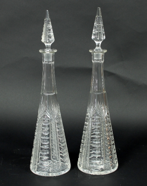 A pair of tall cut glass decanters with circular bases,