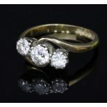 A diamond three-stone ring in a crossover setting to an 18ct gold shank,